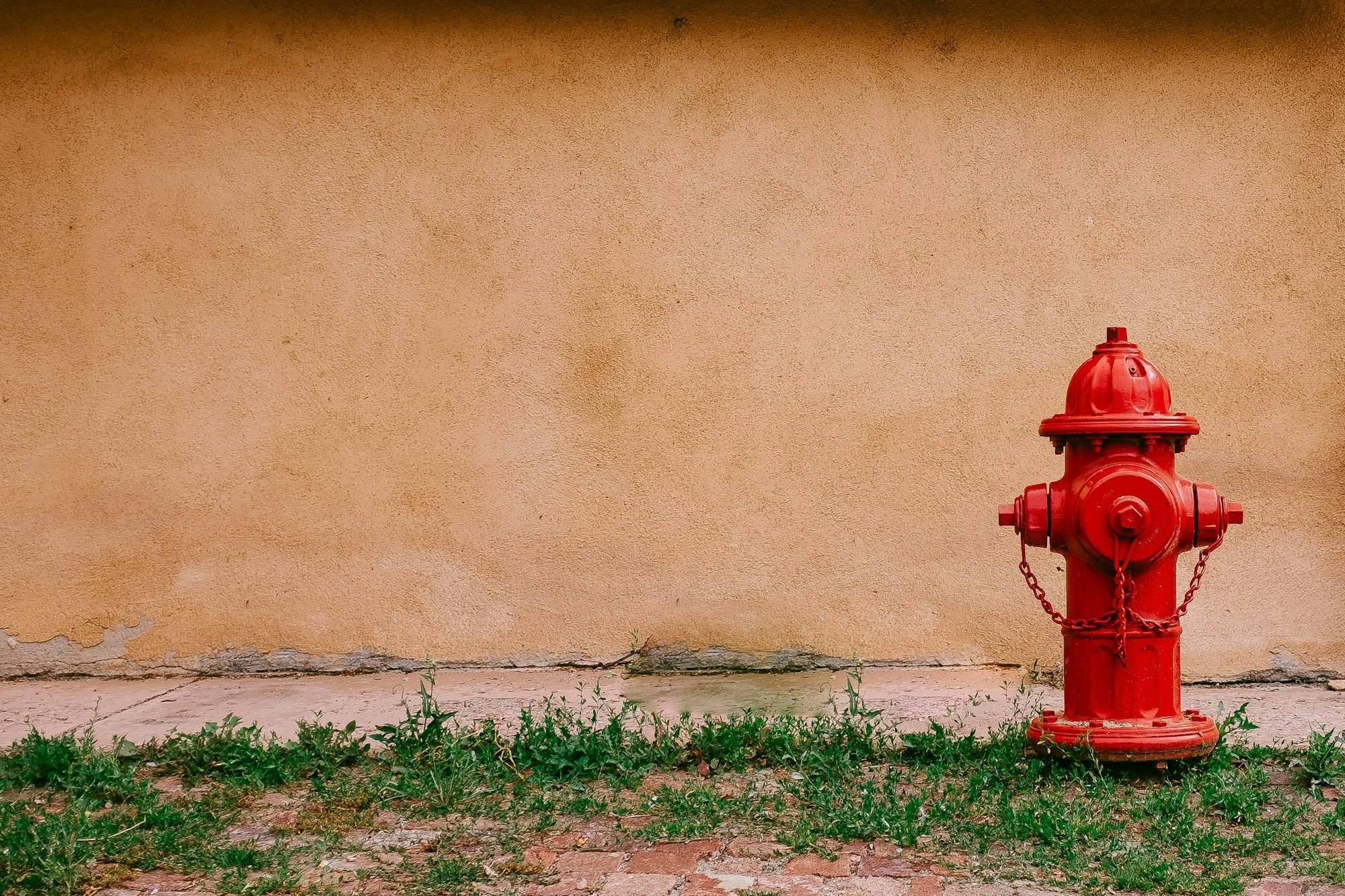 Hidrante rojo junto a un muro ocre